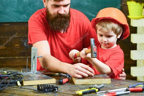 Padre con barba enseñando a su hijo a usar herramientas martilleo