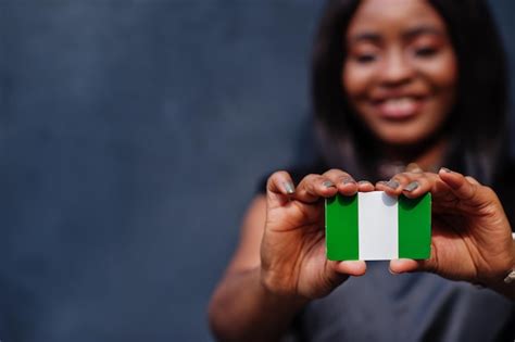 Mujer africana sostiene una pequeña bandera de nigeria en las manos