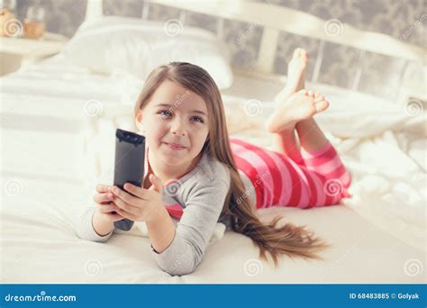 Niña Que Miente En Cama Con Una TV Teledirigida Imagen de archivo