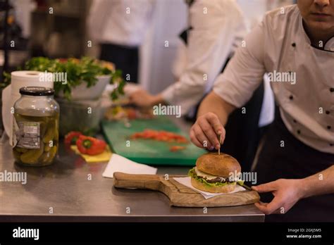 Master Chef Putting Toothpick On A Burger In The Kitchen Stock Photo