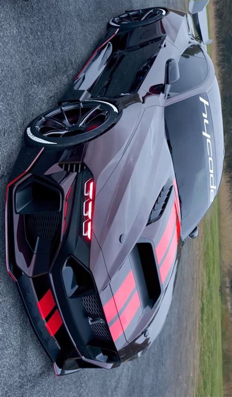 A Grey And Red Sports Car Parked On The Side Of A Road With Grass In