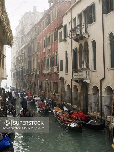 A View Of A Narrow Canal Crowded With Boats And Traditional Gondolas