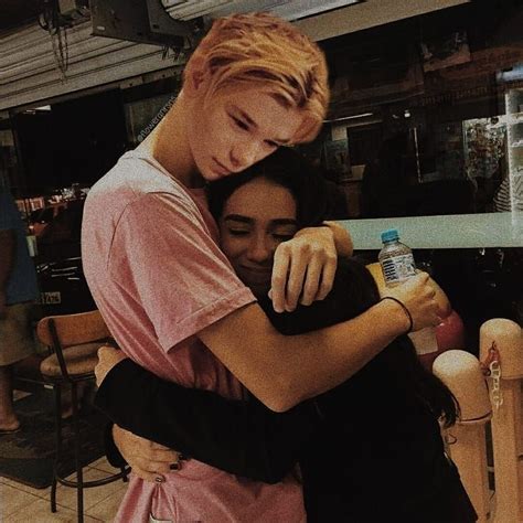 Two People Hugging Each Other In Front Of A Counter Top With Chairs And