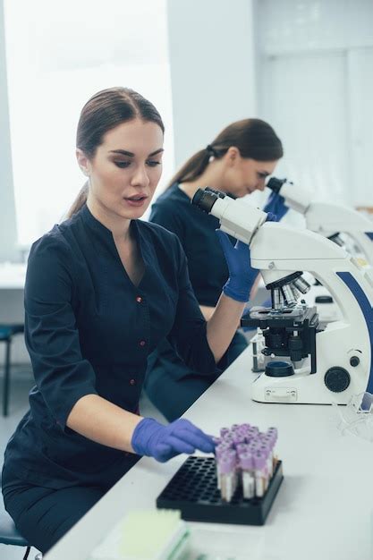 Cient Fica De Laboratorio Femenina Cuidadosa Sentada Cerca De Su Colega