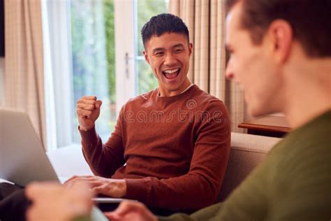 Loving Same Sex Male Couple Cuddling On Sofa At Home Together Stock