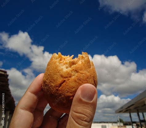 Holding a COXINHA DE FRANGO and having blue sky with cloud as ...