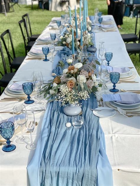 The Table Is Set With Blue And White Dishes Silverware And Candlesticks