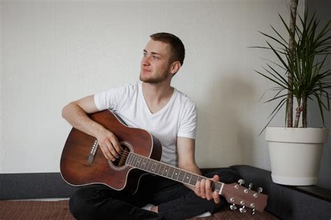 Premium Photo A Man In A White Tshirt Playing Guitar At Homexa