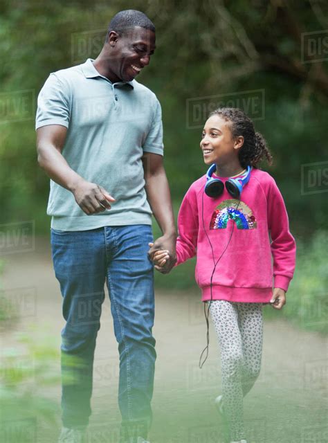 Happy Father And Daughter Holding Hands Walking On Park Path Stock