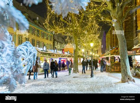 Tourists Enjoy The Christmas Market During Snowfall In Colmar Wine