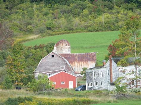 An Old Barn Sits In The Middle Of A Green Field With Trees And Grass