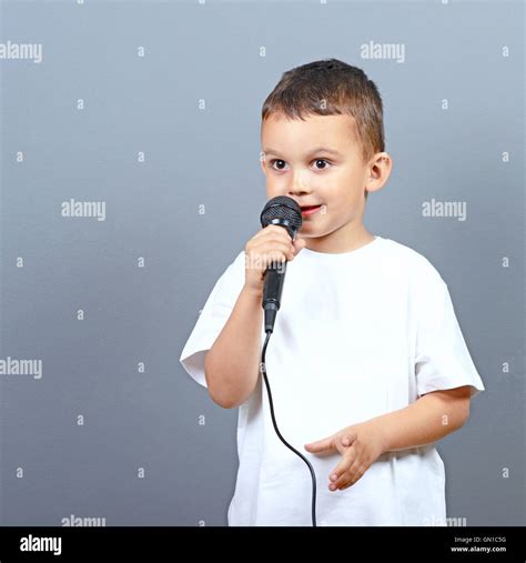 Cute Little Boy Kid Singing On Microphone Against Gray Background Stock