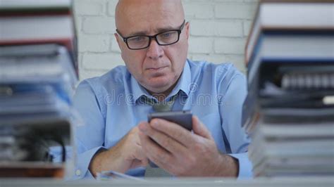 Businessman Wearing Eyeglasses Text Using Cellphone In Office Stock