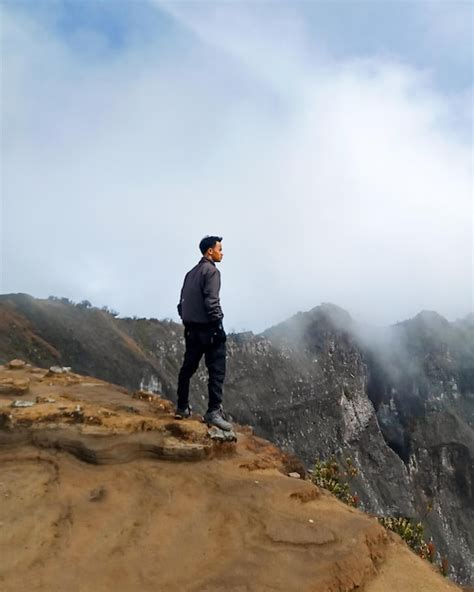 Una Persona De Pie En La Cima De Una Monta A Al Borde De Un Acantilado