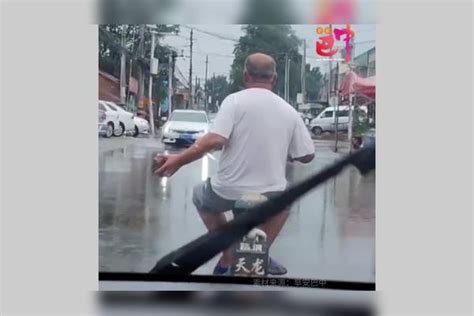 下雨天网友开车前面，一大爷手拿砖头骑电动车