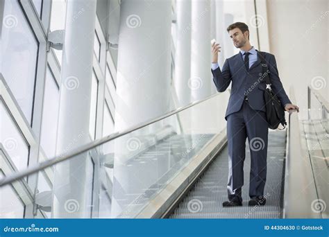 Business Man Sitting Talking On Cell Phone While On Escalator Stock