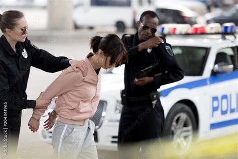 Policewoman Holding Arrested Young Woman While Her Partner Talking On