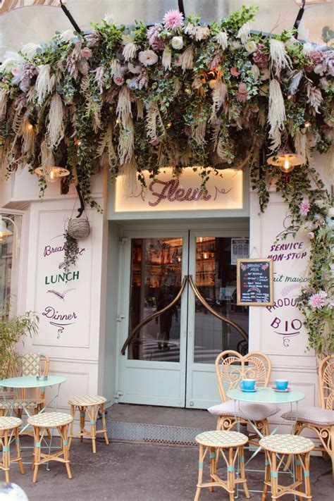 The Outside Of A Restaurant With Tables And Chairs Covered In Greenery