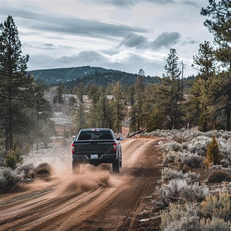 Premium Photo | A jeep driving down a dirt road with a mountain in the ...