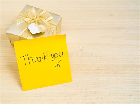 Thank You Words On Sticky Note With Gold Gift Box On Wood Background