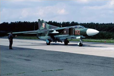 A Fighter Jet Sitting On Top Of An Airport Tarmac Next To A Man