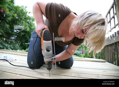 Female Laying Decking In The Garden And Using The Drill To Screw In The