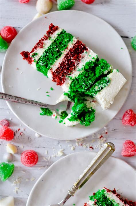 Two Slices Of Cake With Green And Red Frosting On White Plates Next To