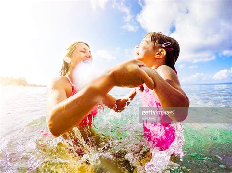 Mother And Daughter Jumping In Sea Together And Holding Hands High Res