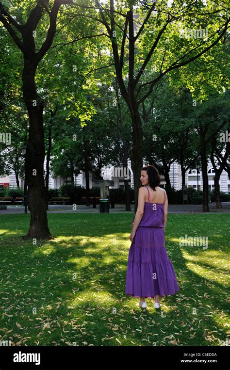 Young Woman Wearing Purple Dress Standing In A Park Outdoors Stock