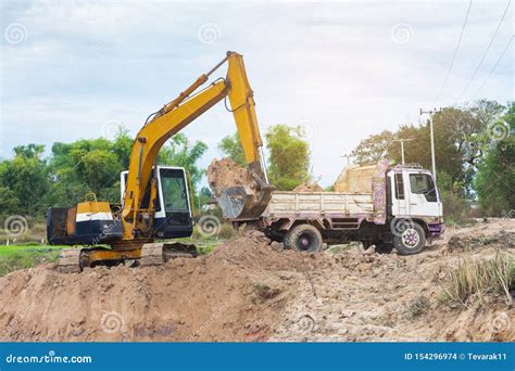 Yellow Excavator Machine Loading Soil Into A Dump Truck At Construction