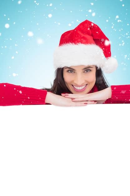 Premium Photo Beauty Brunette In Santa Hat Smiling At Camera Against Blue Background With Vignette