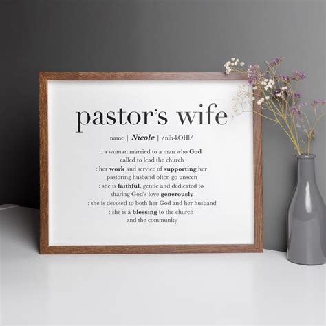 A Vase With Flowers Next To A Framed Poster That Says Pastor S Wife On It