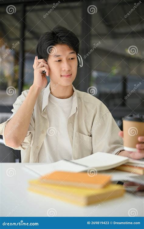 Portrait Of Happy Asian Man Listening To Music Through Headphones While