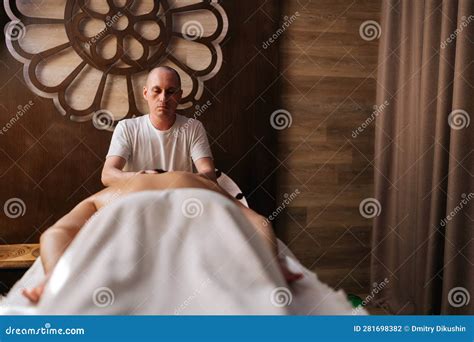 Portrait Of Focused Professional Male Masseur Using Massage Oil For