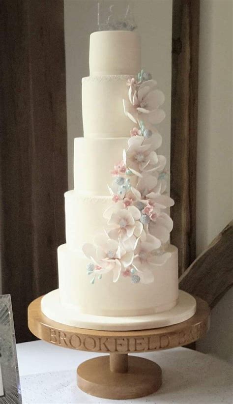 A Three Tiered White Wedding Cake With Pink And Blue Flowers On The