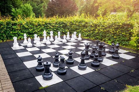 Large Outdoor Chess Game On A Garden Terrace In A Yard With A Green Hedge And Sunshine Stock