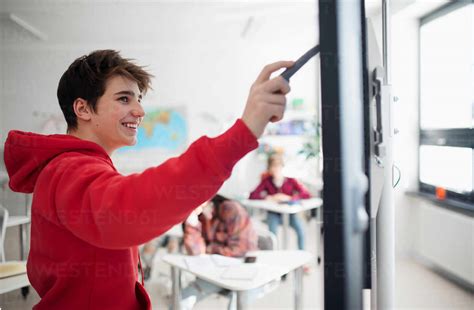 A college student explaining some ideas on a touch TV in classroom. stock photo