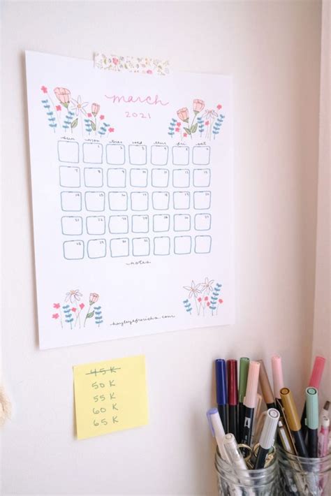 a calendar is hanging on the wall next to pens and pencils in buckets