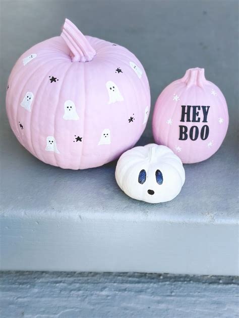 Two Pink Pumpkins With Ghost Faces Painted On Them One Is White And