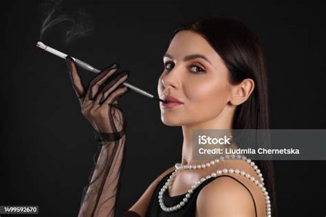 Woman Using Long Cigarette Holder For Smoking On Black Background Stock