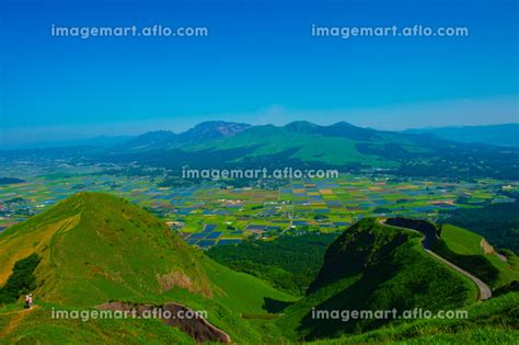 阿蘇外輪の草原からパッチワークの田園風景と雄大な阿蘇五岳を望むの写真素材 [185376969] イメージマート