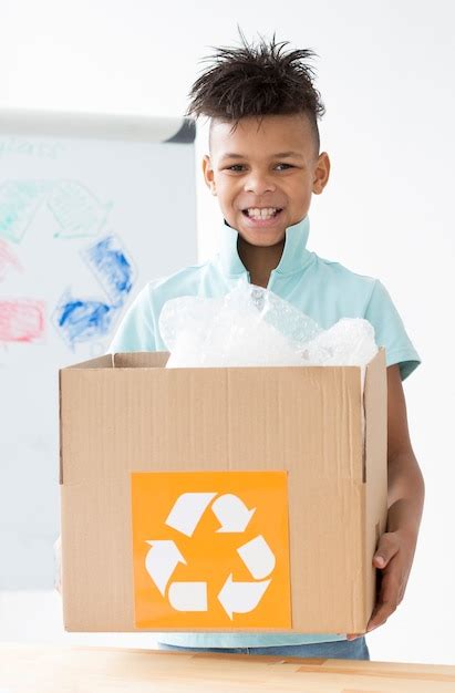 Retrato de menino feliz segurando a caixa de reciclagem Foto Grátis