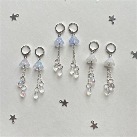 Six Pairs Of Dangling Charms On A White Surface With Stars And Tiny