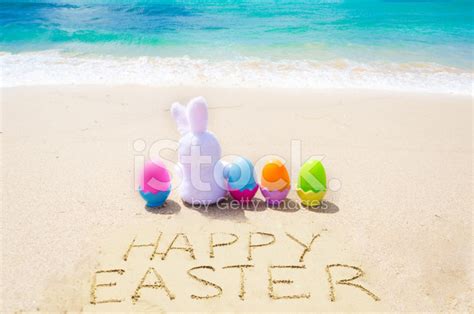 Sign Happy Easter With Bunny And Eggs On The Beach Stock Photo