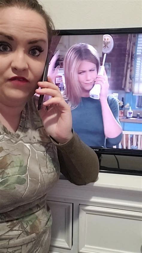 a woman holding a cell phone to her ear while standing in front of a ...