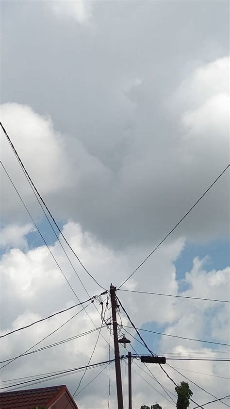 Telephone Poles And Power Lines Against A Cloudy Sky