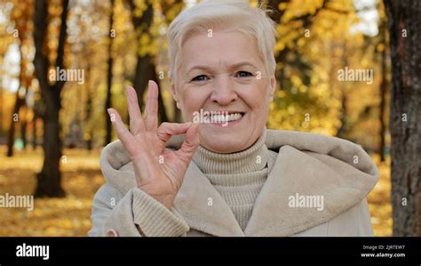 Happy Elderly Woman Joyfully Smiling Standing In Autumn Park Mature