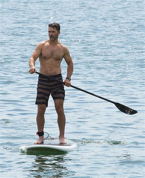 A Man Standing On A Paddle Board In The Water With His Oar Behind Him