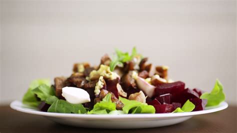 Salad with boiled beets, fried eggplants, herbs and arugula in a plate ...