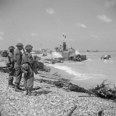 Three Beach Group troops look out from Queen beach,Sword Beach, littered with beached landing ...